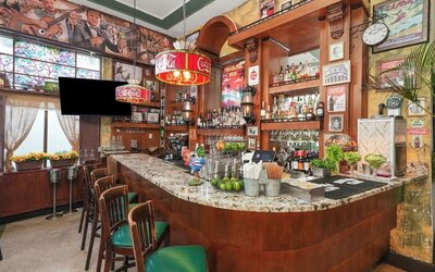Retro-style bar with wood finishes, marble counter, vintage posters, and stocked shelves of bottles at Hotel Chelsea, A South Beach Group Hotel.