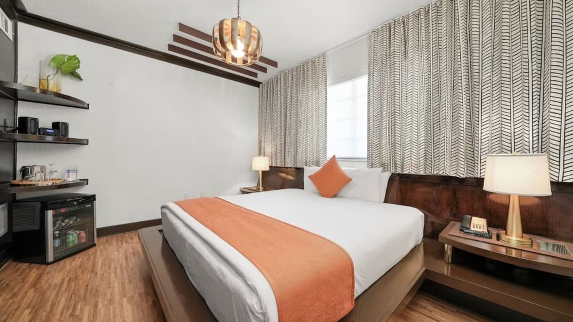 Spacious bedroom with platform bed, orange runner, bedside lighting, and minibar area at Hotel Chelsea, A South Beach Group Hotel.