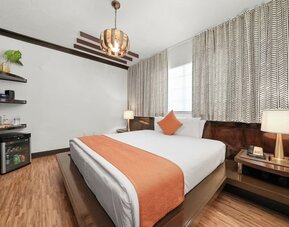 Spacious bedroom with platform bed, orange runner, bedside lighting, and minibar area at Hotel Chelsea, A South Beach Group Hotel.