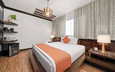 Spacious bedroom with platform bed, orange runner, bedside lighting, and minibar area at Hotel Chelsea, A South Beach Group Hotel.