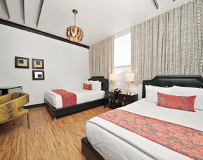 Guest room with two beds, patterned runners, bedside lamps, desk area, and wood flooring at Hotel Chelsea, A South Beach Group Hotel.