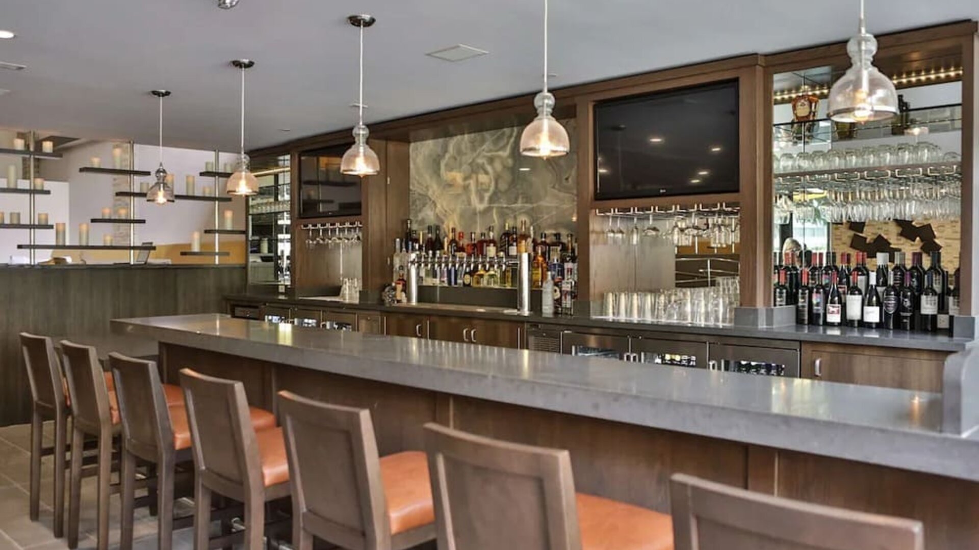 Bar area with high counter seating, pendant lighting, wine display, and backlit shelves at DoubleTree By Hilton Los Angeles Downtown.