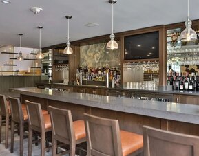 Bar area with high counter seating, pendant lighting, wine display, and backlit shelves at DoubleTree By Hilton Los Angeles Downtown.