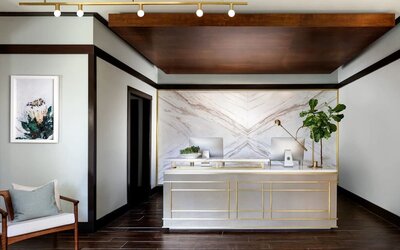 Reception desk with marble backdrop, wood accents, and minimalist decor in a modern lobby setting at The Ambrose Hotel Santa Monica.