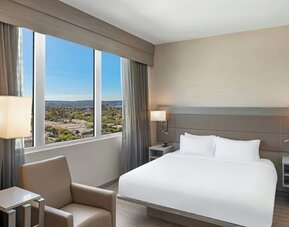 Guest room with king bed, large window view, bedside lighting, and minimal modern decor at AC Hotel By Marriott Beverly Hills.