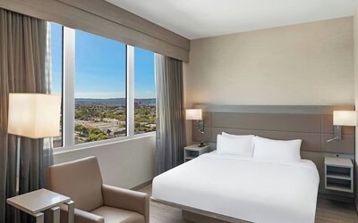 Guest room with king bed, large window view, bedside lighting, and minimal modern decor at AC Hotel By Marriott Beverly Hills.