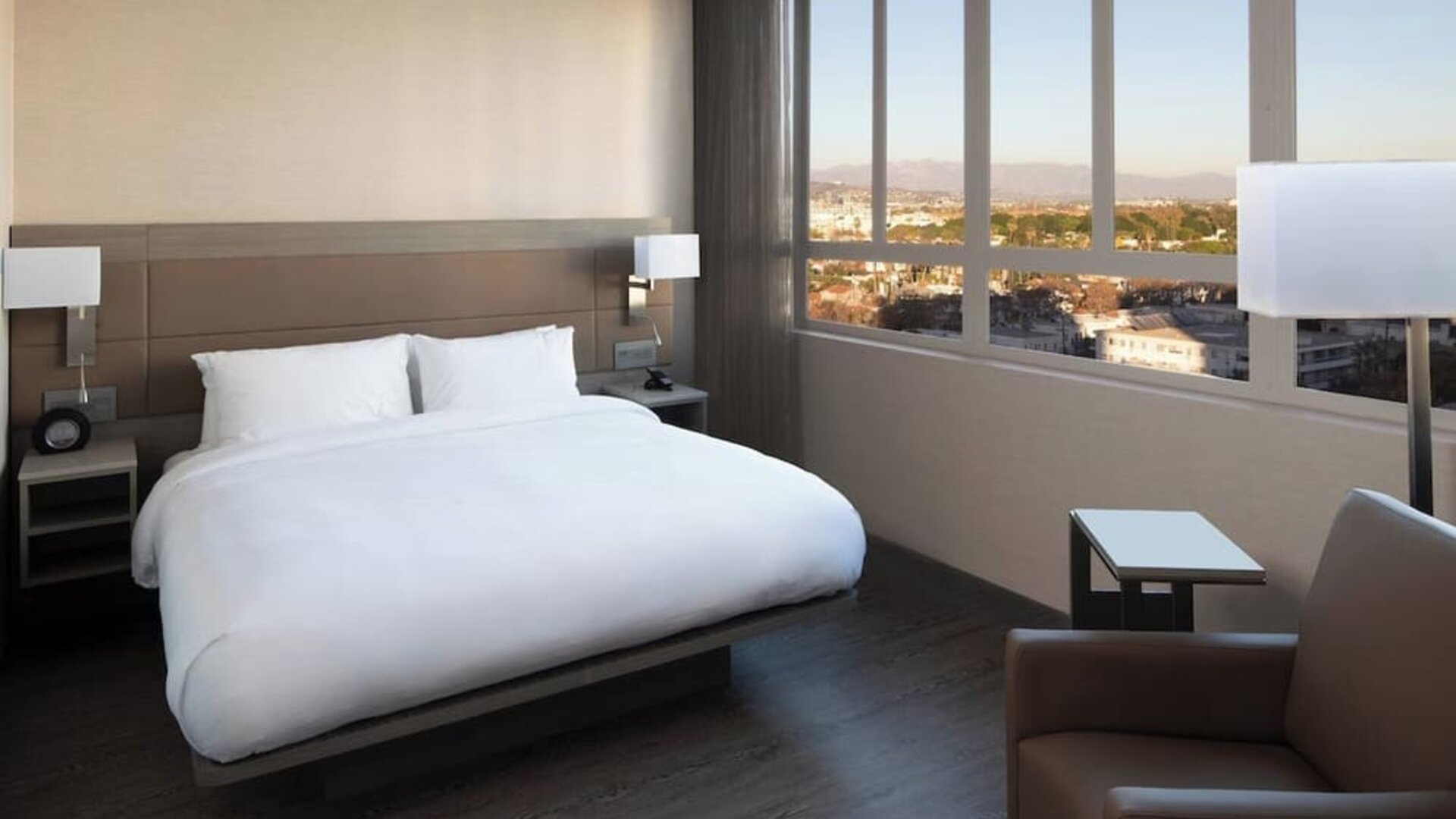 Guest room with king bed, floor-to-ceiling windows, city views, and modern furnishings at AC Hotel By Marriott Beverly Hills.