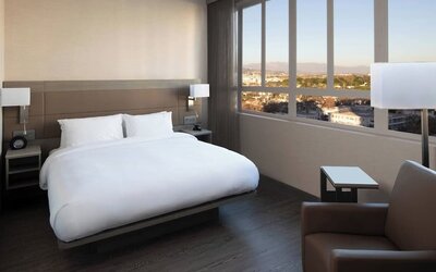 Guest room with king bed, floor-to-ceiling windows, city views, and modern furnishings at AC Hotel By Marriott Beverly Hills.