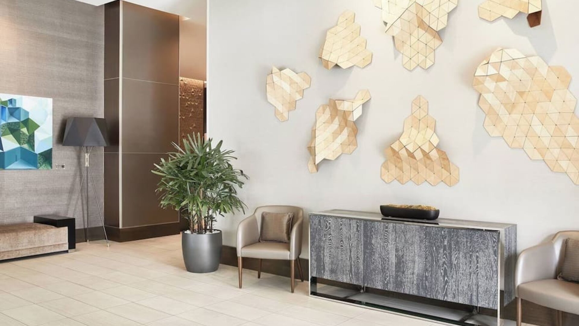 Lobby seating area with geometric wall art, potted plants, and contemporary furniture at AC Hotel By Marriott Beverly Hills.