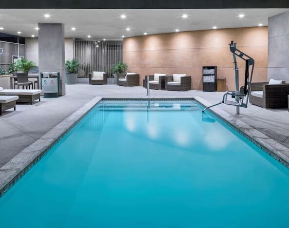 Indoor pool area with seating, accessibility lift, and ambient lighting at Hampton Inn & Suites Los Angeles / Hollywood.