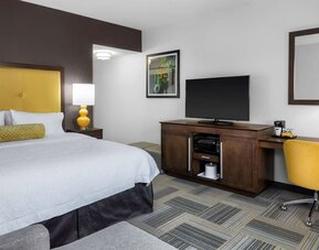Guest room with king bed, yellow upholstered headboard, work desk, TV, and modern furnishings at Hampton Inn & Suites Los Angeles / Hollywood.