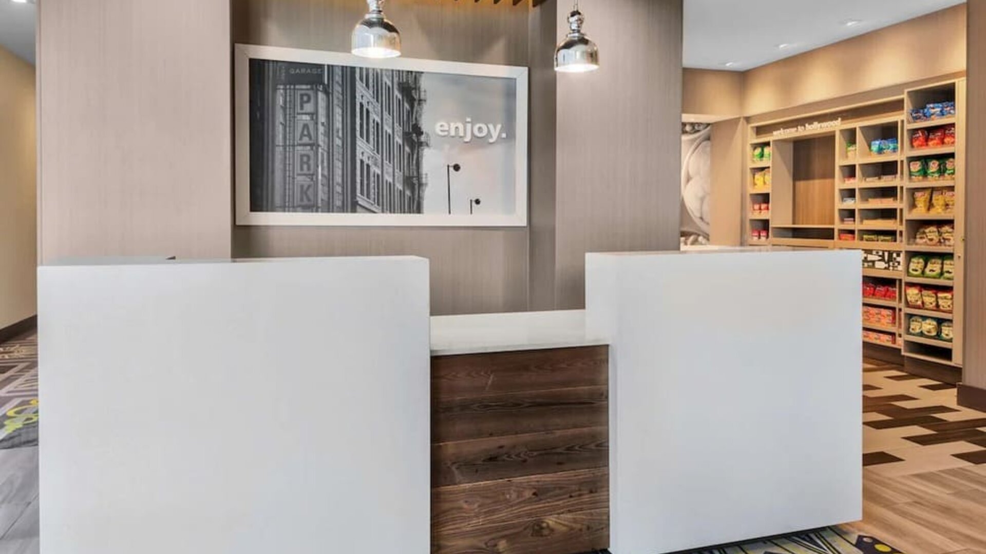 Reception desk area with modern design, wood accents, and small retail/snack section at Hampton Inn & Suites Los Angeles / Hollywood.