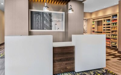 Reception desk area with modern design, wood accents, and small retail/snack section at Hampton Inn & Suites Los Angeles / Hollywood.