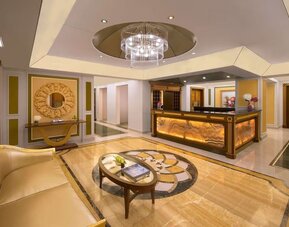 Reception area with curved desk, chandelier ceiling feature, and gold-accented décor