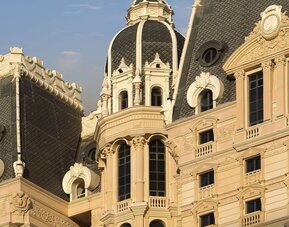 Close view of ornate building façade featuring domed roof, decorative moldings, and tall windows