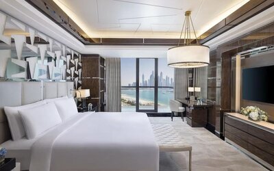 King bedroom with large bed, decorative headboard, desk area, and balcony with marina skyline view