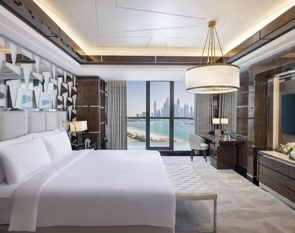 King bedroom with large bed, decorative headboard, desk area, and balcony with marina skyline view