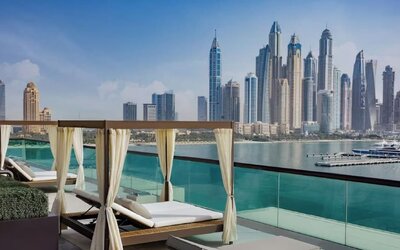 Private cabanas with cushioned loungers on terrace overlooking calm water and modern skyline