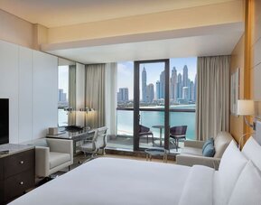 King bedroom with large bed, decorative headboard, desk area, and balcony with marina skyline view