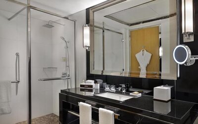 Modern bathroom with glass walk-in shower, black vanity, large mirror, and neatly arranged amenities