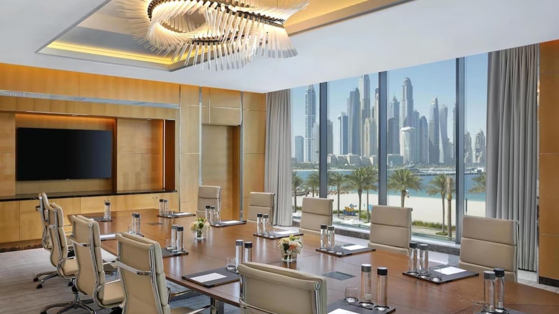 Conference room with long table, leather chairs, and large windows overlooking waterfront skyline