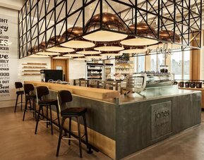 Stylish café bar with high stools, espresso machine, pendant lighting, and warm wood and metal finishes