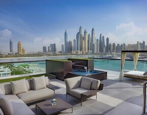 Rooftop lounge with seating, small plunge pool, cabana daybeds, and panoramic skyline views