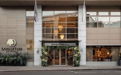 Street view of DoubleTree by Hilton entrance with large windows and floral decorations around doors