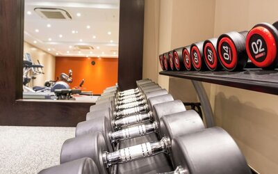 Fitness center with free weights, mirrored wall, and cardio machines in the background