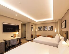 Contemporary room with two queen beds, wood flooring, framed artwork, and recessed ceiling lights