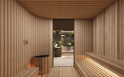 Wood-lined sauna room with bench seating, heated stones, and doorway to adjacent spa area