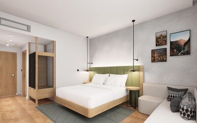 King guest room with green upholstered headboard, wood accents, pendant lights, and small sofa