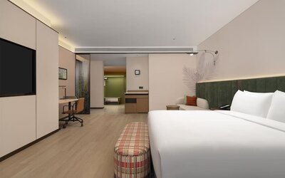 King guest room with plaid bench, workspace, cushioned seating area, and soft recessed lighting