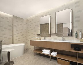 Spacious bathroom with freestanding bathtub, double illuminated mirrors, and long marble vanity