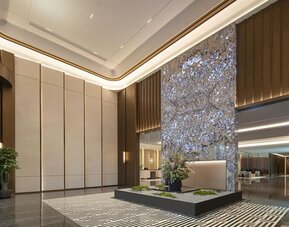 Grand reception lobby with tall decorative art wall, polished floors, and warm accent lighting