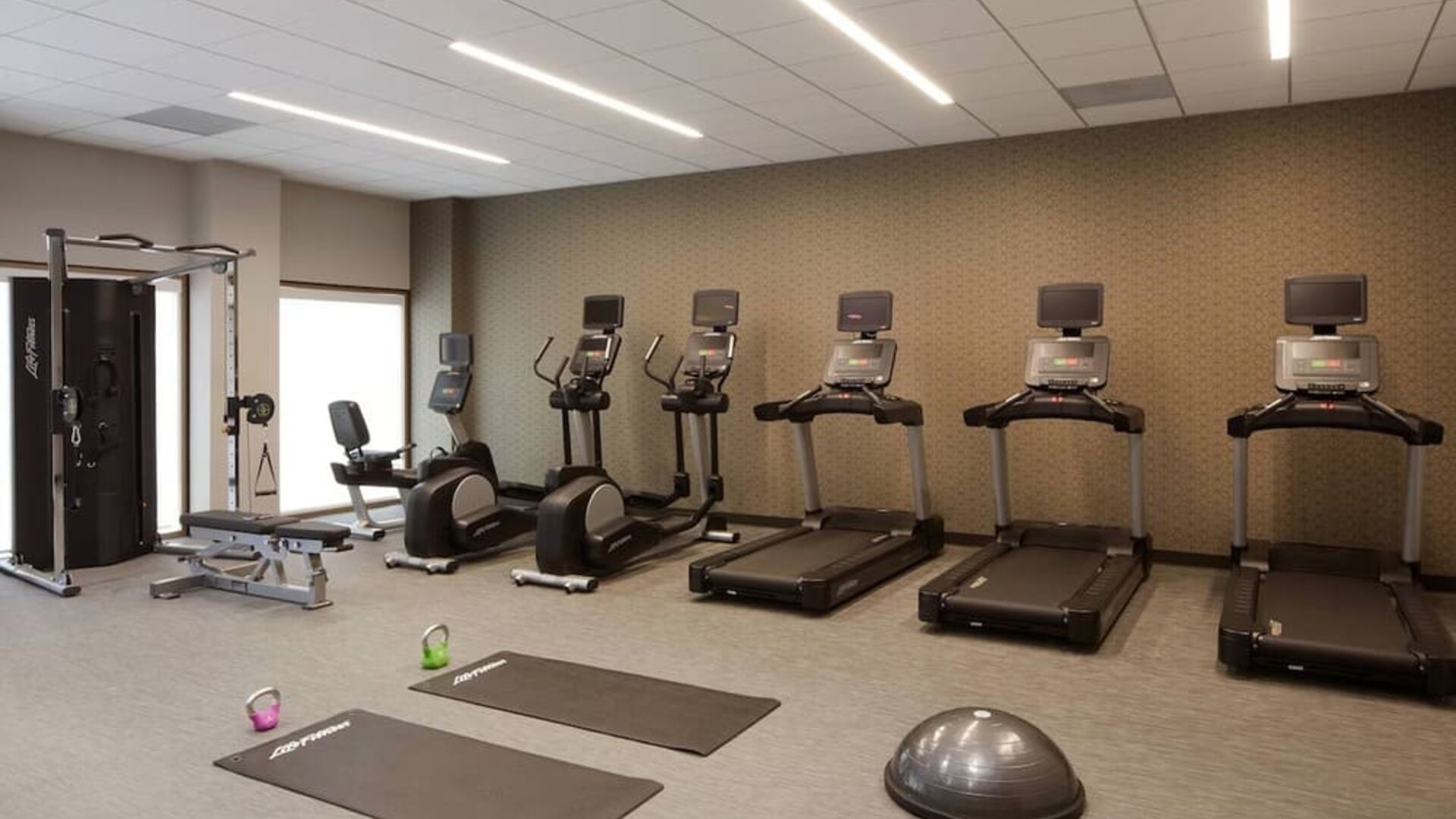 Gym area featuring cardio machines, yoga mats, kettlebells, and functional workout equipment at Courtyard By Marriott Los Angeles LAX/Century Boulevard.