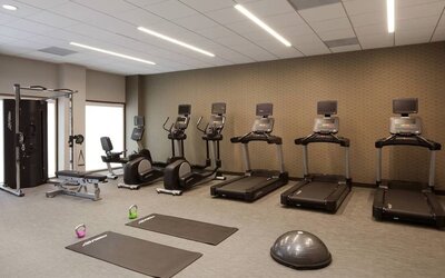 Gym area featuring cardio machines, yoga mats, kettlebells, and functional workout equipment at Courtyard By Marriott Los Angeles LAX/Century Boulevard.