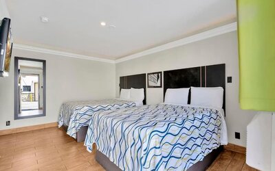 Guest room with two double beds, tiled flooring, modern lighting, and wall-mounted TV at Mid City Inn - Los Angeles.