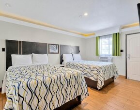 Spacious double-bed guest room with wood-style flooring, modern décor, and bright accent curtains at Mid City Inn - Los Angeles.