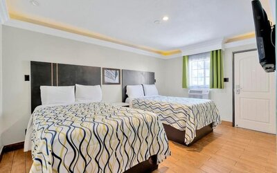 Spacious double-bed guest room with wood-style flooring, modern décor, and bright accent curtains at Mid City Inn - Los Angeles.