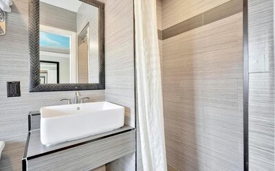 Contemporary bathroom with modern sink vanity, textured wall tiles, and walk-in shower at Mid City Inn - Los Angeles.