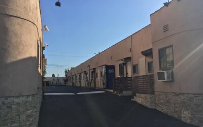 Exterior driveway view showing motel-style room entrances and parking access at Mid City Inn - Los Angeles.