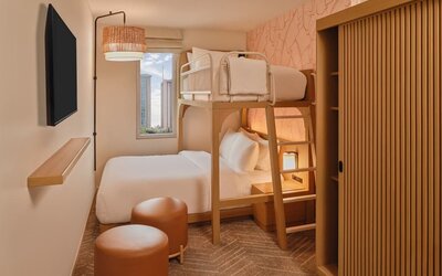 Guest room with two beds, modern headboard, and balcony seating area at The Ambassador Hotel Of Waikiki.