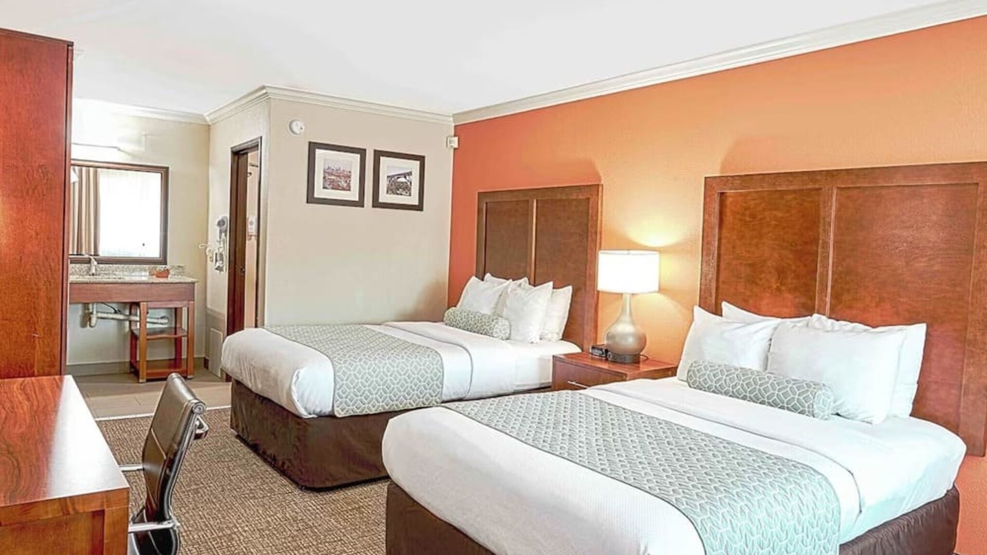 Double queen room with two beds, bedside lighting, vanity area, and patterned carpet at The Hills Inn Eagle Rock.
