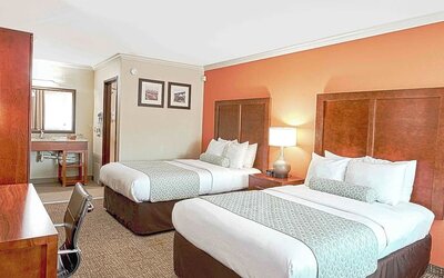 Double queen room with two beds, bedside lighting, vanity area, and patterned carpet at The Hills Inn Eagle Rock.
