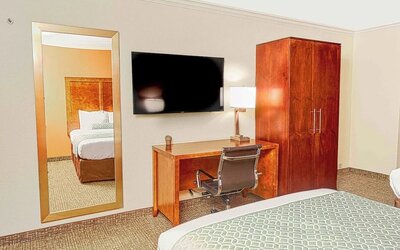 Guest room with mounted TV, wooden wardrobe, desk workspace, and full-length mirror at The Hills Inn Eagle Rock.