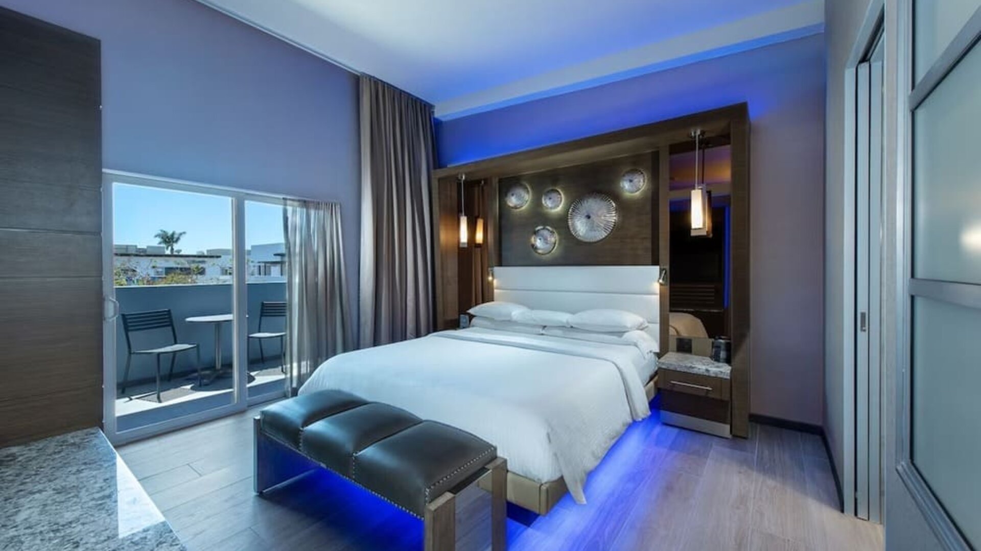 Spacious king room with blue accent lighting, balcony access, and modern wood finishes at Shade Hotel Manhattan Beach.