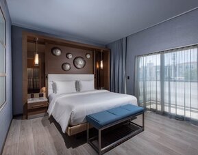 Contemporary king room with balcony doors, bench seating, and floor-to-ceiling curtains at Shade Hotel Manhattan Beach.
