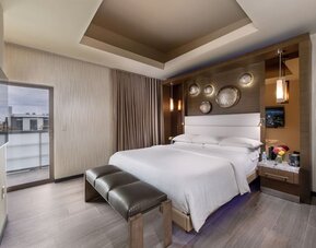 King bedroom with modern decor, padded bench, balcony access, and decorative wall accents at Shade Hotel Manhattan Beach.