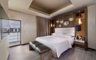 King bedroom with modern decor, padded bench, balcony access, and decorative wall accents at Shade Hotel Manhattan Beach.